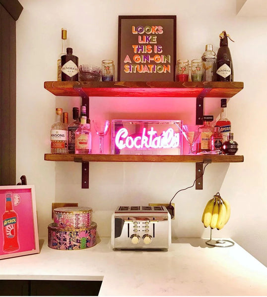 Neonschild "Cocktails" in einem Regal 